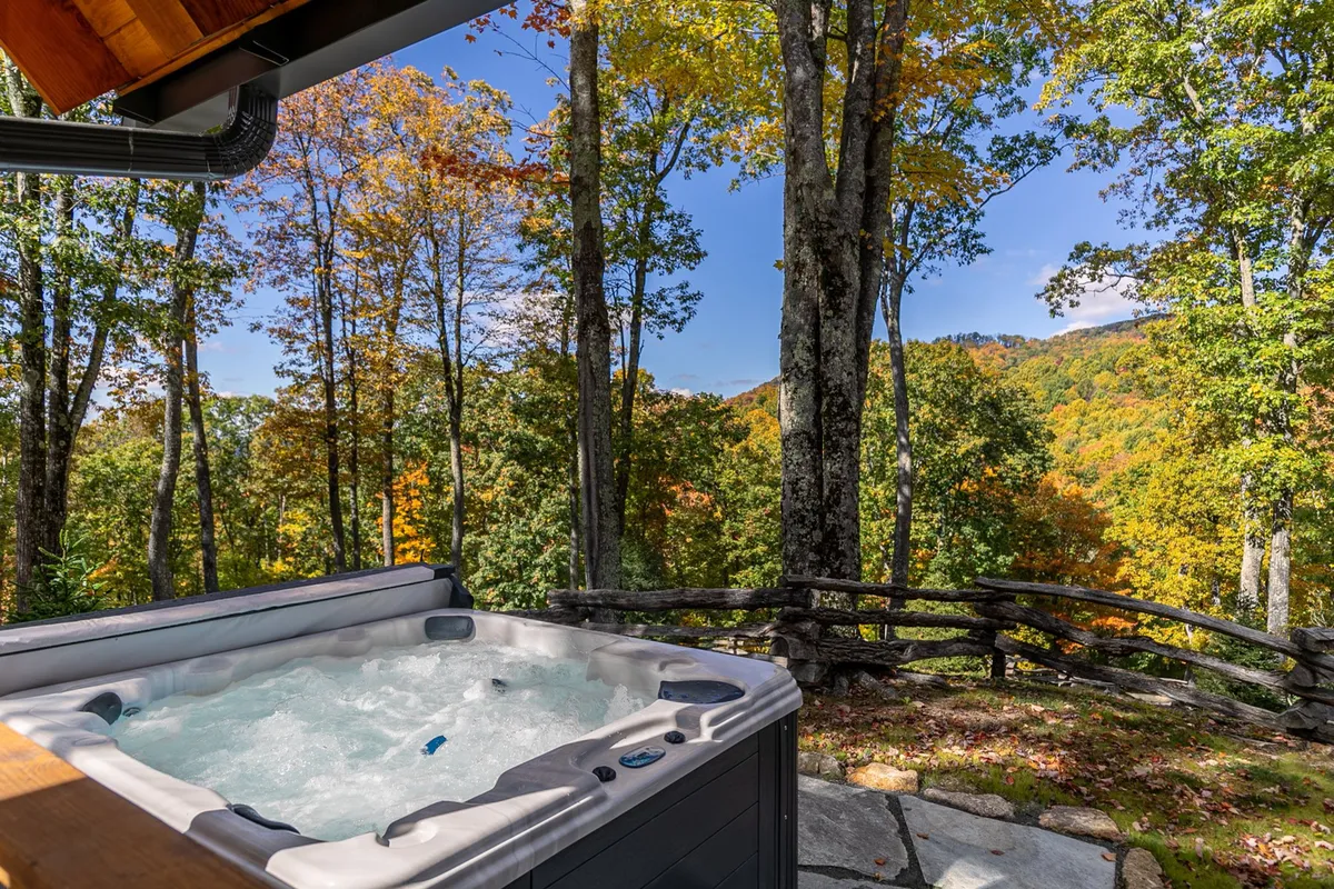 A tranquil outdoor hot tub set among tall trees with a panoramic mountain view. The scene suggests a peaceful, social atmosphere, perfect for unwinding after a day of adventure. The natural surroundings highlight the luxury and immersion in nature available to residents and guests.