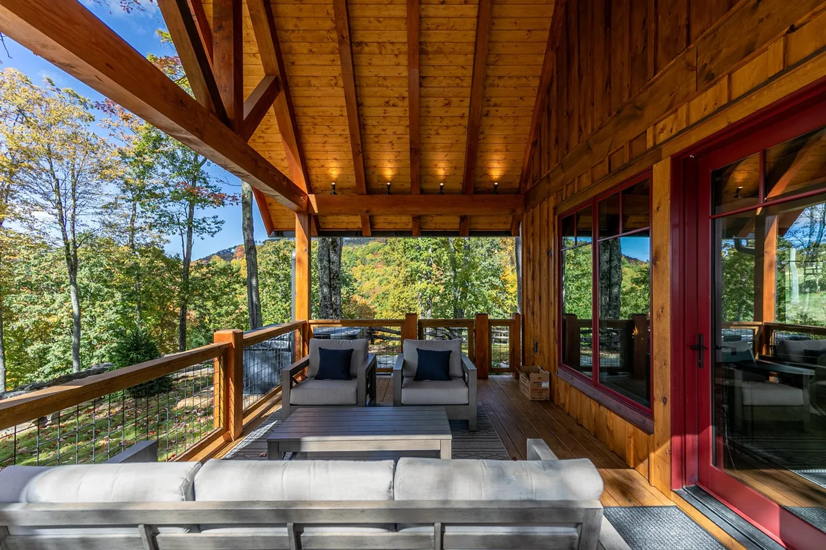This image captures a tranquil outdoor lounge area with wooden beams, comfortable seating, and sweeping views of natural scenery—perfect for relaxing and taking in the surroundings. The warm light suggests a sunset, enhancing the inviting mood.